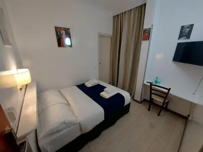 a bedroom with a bed and a desk with a television at Hotel Positano 2 MIMOSA in Rome