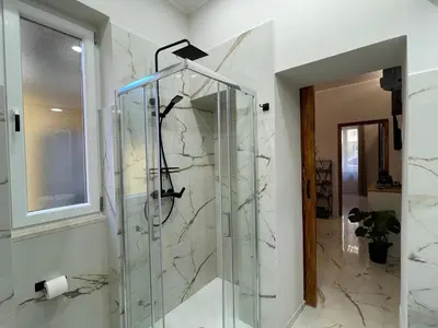 a glass shower in a bathroom with marble walls at Il giardinetto di Ponte Milvio in Rome