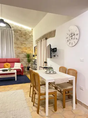 a living room with a table and chairs and a clock at Dimora Ardeatina in Rome