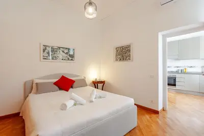 a white bedroom with a white bed with red pillows at Luxury Penthouse with Terrace by Spanish Steps in Rome