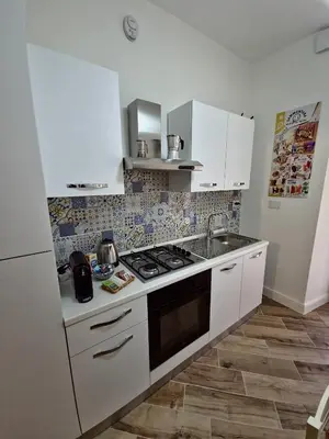 a kitchen with white cabinets and a stove top oven at Casa Milly in Rome