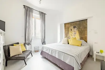 a white bedroom with a large bed and a chair at Appartamento Moderno-H2OME nuovo in Rome