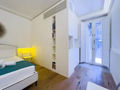 a white bedroom with a bed and a sliding glass door at Gold Suite 5 minuti dal Colosseo in Rome