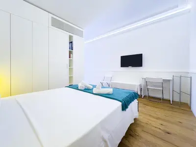 a white bedroom with a bed and a tv at Gold Suite 5 minuti dal Colosseo in Rome