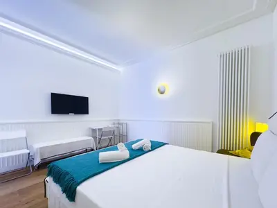 a white bedroom with a bed and a flat screen tv at Gold Suite 5 minuti dal Colosseo in Rome