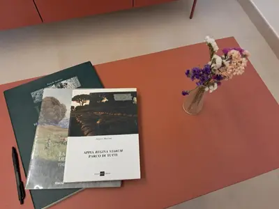 a table with a book and a vase of flowers at Casa dei Parchi in Rome