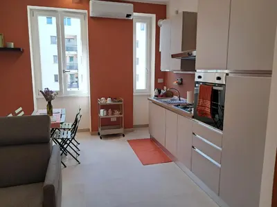 a kitchen with orange walls and white cabinets and a table at Casa dei Parchi in Rome