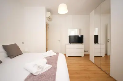 a white bedroom with a bed and a tv at Maison Tiburtina by Ghor in Rome