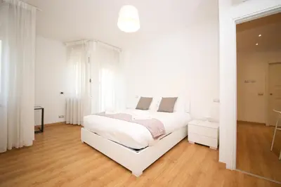 a white bedroom with a large white bed and wooden floors at Maison Tiburtina by Ghor in Rome