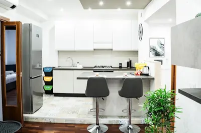 a kitchen with white cabinets and two stools at Vaticano-Cornelia Luxury Home in Rome