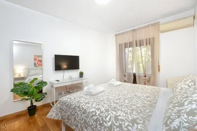 a white bedroom with a bed and a tv at Your Place in Rome Apartments in Rome
