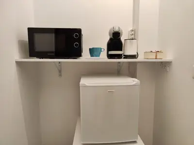 a microwave sitting on a shelf above a trash can at Rome Cozy Room in Rome