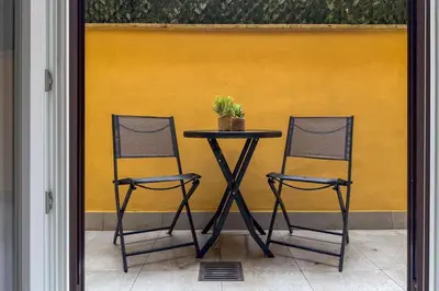 two chairs and a table in front of a yellow wall at GF Harmony Suite Colosseo in Rome