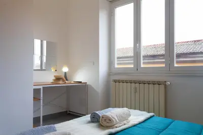a bedroom with a bed and a desk and two windows at Saulo Boutique Apartment in Rome