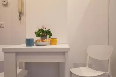 a white table with a bowl of fruit and a chair at Saulo Boutique Apartment in Rome