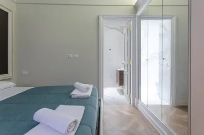 a white bedroom with a green bed and a mirror at Spanish Steps Luxury Apartment in Rome