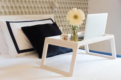 a white table with a vase of flowers and a laptop on it at Colosseum suites by Glen in Rome