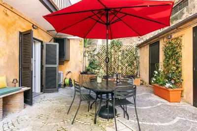 a table with a red umbrella on a patio at Rome As You Feel - Trastevere Nest with Secret Patio in Rome
