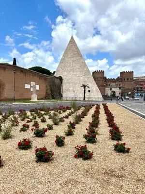 a hedge of flowers in front of a pyramid at Casa Dea Piramide in Rome