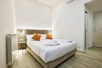 a bedroom with a large white bed with orange pillows at Urban Guesthouse Monti in Rome