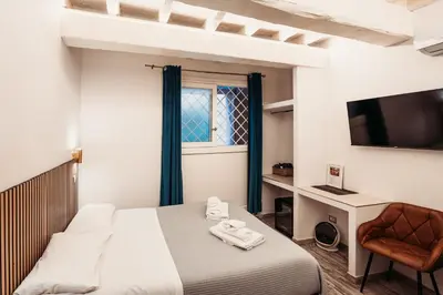 a bedroom with a bed and a chair and a television at NL Trastevere in Rome