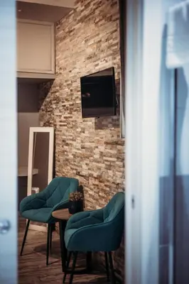 a living room with two chairs and a tv on a brick wall at NL Trastevere in Rome
