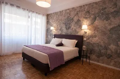 a bedroom with a bed and a wall covered in wallpaper at B&B Roma 474 in Rome