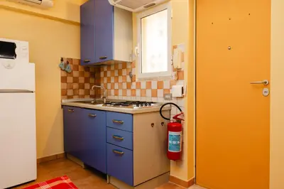 a kitchen with blue cabinets and a red fire extinguisher at Studio House da Pasolini a Mastroianni in Rome