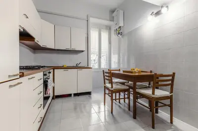 a kitchen with white cabinets and a table and chairs at Ottaviano Vatican Museums Stay 5 min from Metro in Rome
