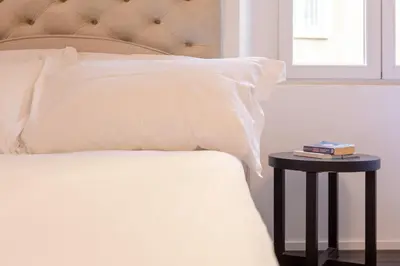 a bed with a white pillow and a side table at Cunabu Sardegna in Rome