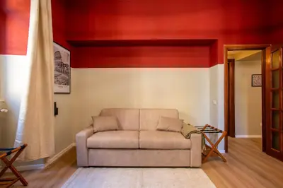 a couch in a living room with a red wall at Urban Oasis Metro B Piramide - 2 subway stations from Colosseo in Rome