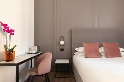 a bedroom with a bed with a desk and a chair at DA ME Suites in Rome