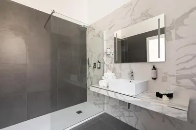 a white bathroom with a sink and a shower at DA ME Suites in Rome