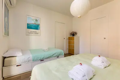 two beds in a room with white walls at Vatican 10 min Modern apartment AC, Wi-Fi, Netflix in Rome