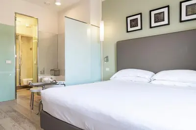 a bedroom with a large white bed and a bathroom at Domus Adriani in Rome