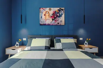 a blue bedroom with a bed and a painting on the wall at OASIS Of PEACE CLOSE TO VATICANO in Rome