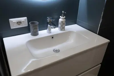 a white sink in a bathroom with a blue wall at 2-Bedroom Roman Gem in Rome