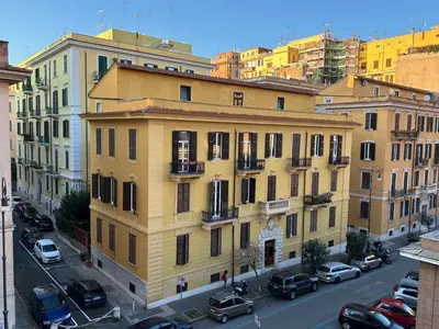 a yellow building on a city street with parked cars at Triade Home in Rome