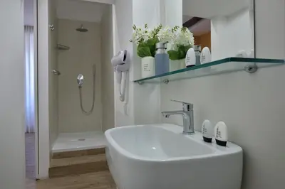 a white bathroom with a sink and a shower at Palazzo Tridente Rooms in Rome