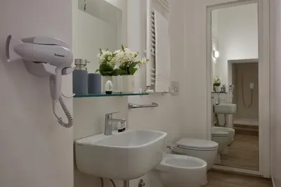 a white bathroom with a sink and a toilet at Palazzo Tridente Rooms in Rome