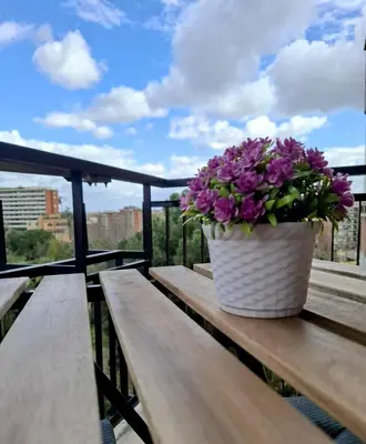 a pot of purple flowers sitting on a wooden bench at Locazione turistica di Alberto in Rome