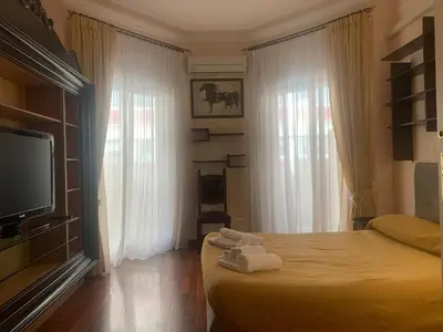 a bedroom with a bed and a tv and windows at Trastevere AURA - Your Roman home with SOUL in Rome