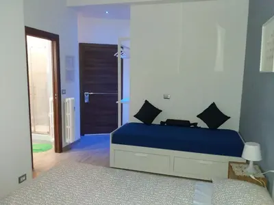 a bedroom with a blue bed and a bathroom at Gloria Vatican Bijou in Rome