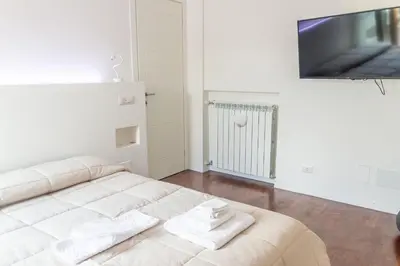a white bed in a room with a flat screen tv at gandino apartment in Rome
