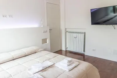 a white living room with a couch and a tv at gandino apartment in Rome