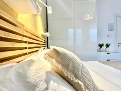 a bedroom with a white bed with a wooden headboard at Saint Peter Rome - Luxury Apartments with 24H Guarded Parking in Rome
