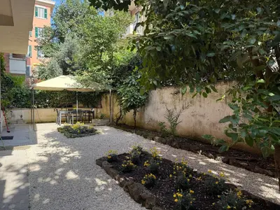 a garden with a table and an umbrella and flowers at Bologna GARDEN HOUSE in Rome