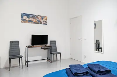 a bedroom with a bed and two chairs and a desk with a television at Lion Renting Vatican Apartment in Rome