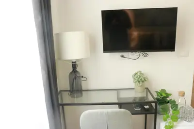 a television on a wall with a chair and a lamp at Giulio Cesare Comfort Rooms in Rome