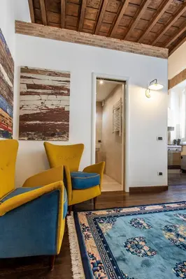 a living room with yellow chairs and a rug at Exclusive House Ghetto in Rome